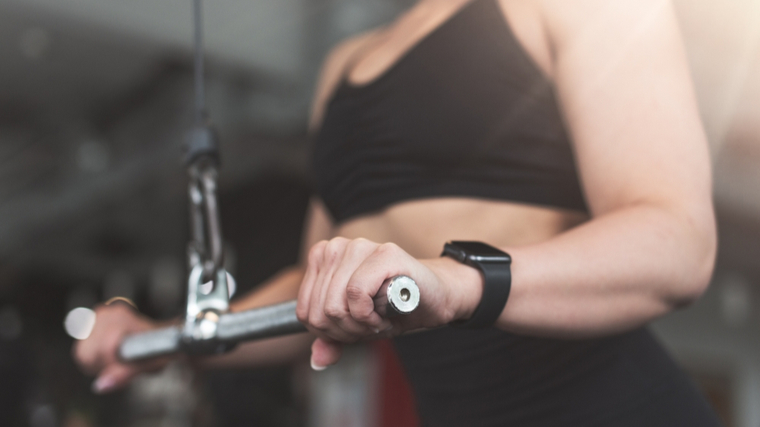 close-up photo of a person's hands holding an exercise bar connected to cable